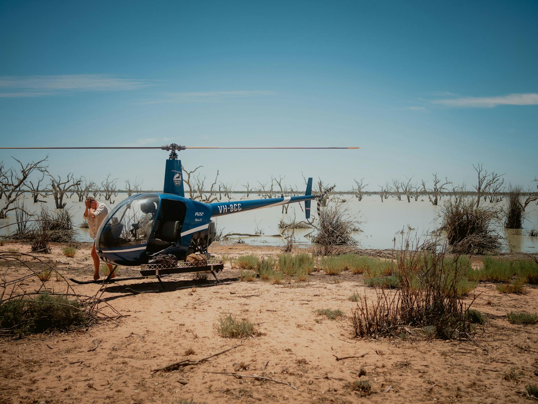 Blue helicopter landed with a lake in the background